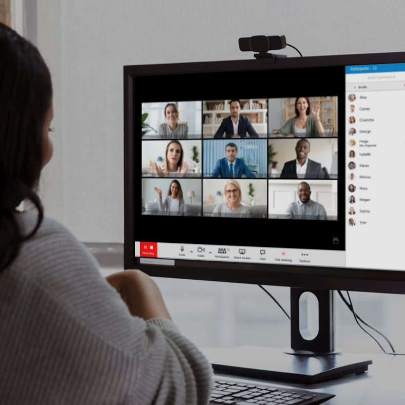 A video call meeting on a screen, many participants smile.