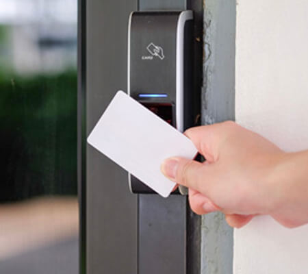 A hand with a white card over an access control reader