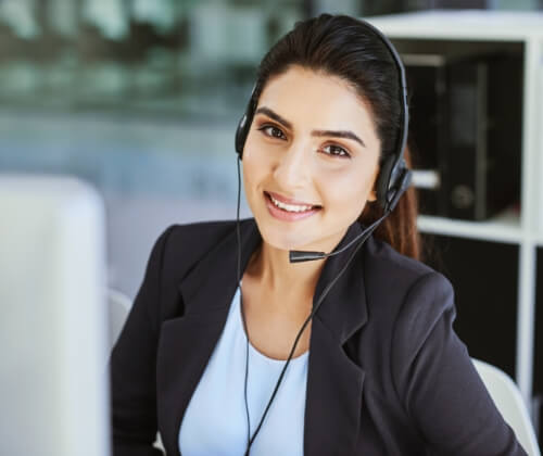 A woman smiling working with a VoIP phone. She's happy with the great service and quality product.